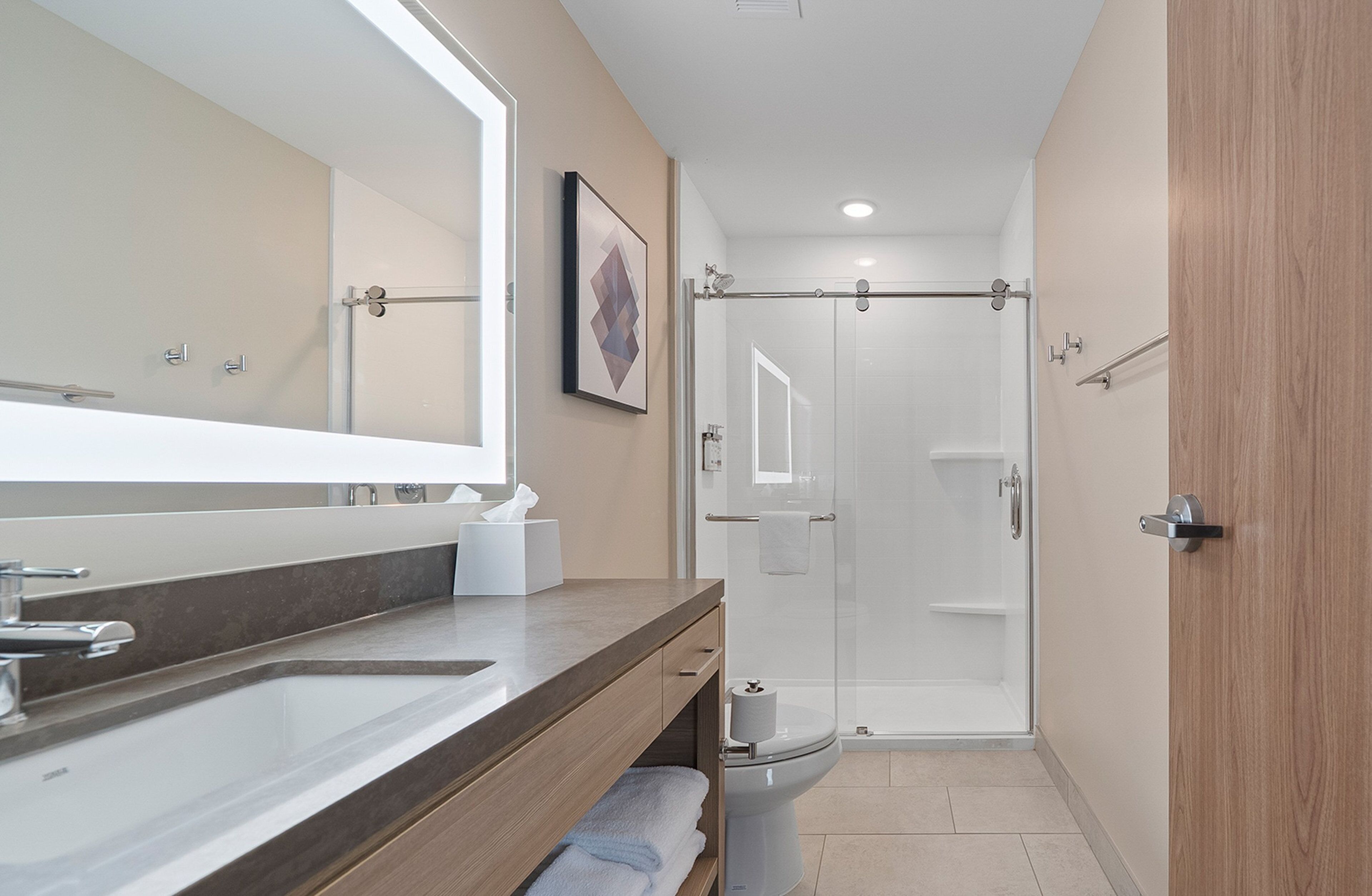 Ein modernes Badezimmer mit großem Spiegel, Waschbecken, Toilette und einer Duschkabine.