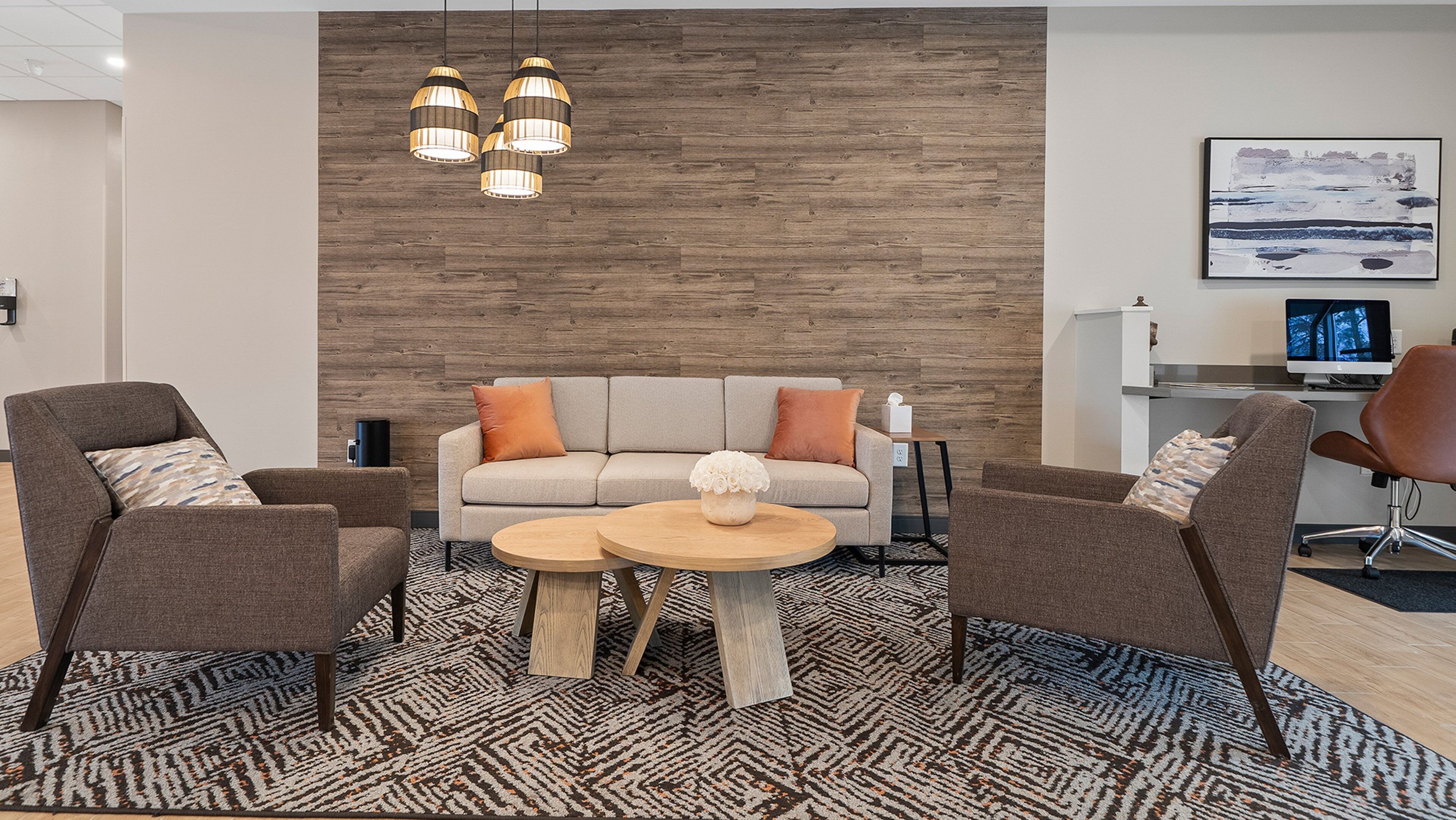 A modern living room with a sofa, two armchairs, a coffee table, and a patterned rug.