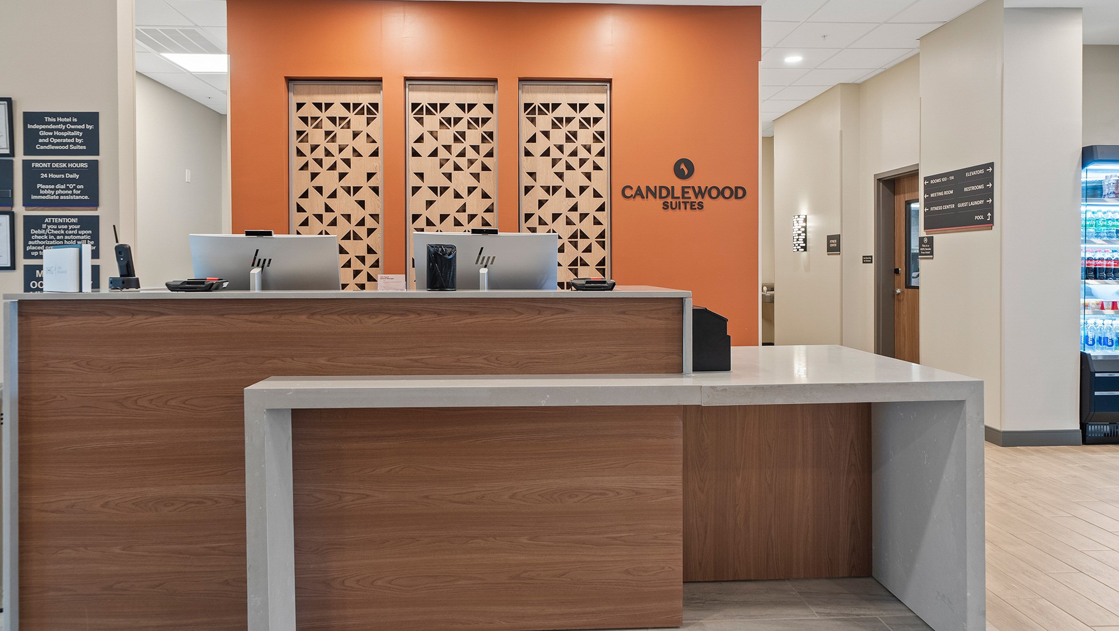 A hotel reception desk with a modern design, including a wooden panel and a sign for Candlewood Suites.
