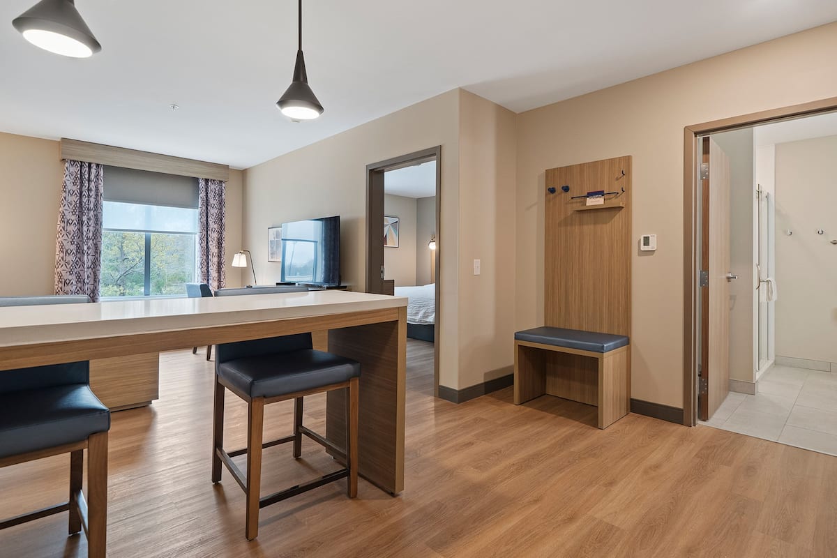 A modern kitchen with a wooden countertop, bar stools, and pendant lighting.