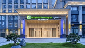 A Holiday Inn Express hotel entrance with a modern facade, large glass windows, and a well-lit entrance area. - Rugao City Center by IHG (Nantong)