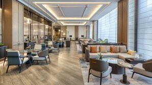 A spacious lobby with modern furnishings, a central seating area, and large windows providing natural light. - Rugao City Center by IHG (Nantong)
