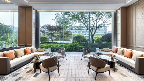 A modern lounge area with a large window offering a view of the cityscape and greenery. - Rugao City Center by IHG (Nantong)