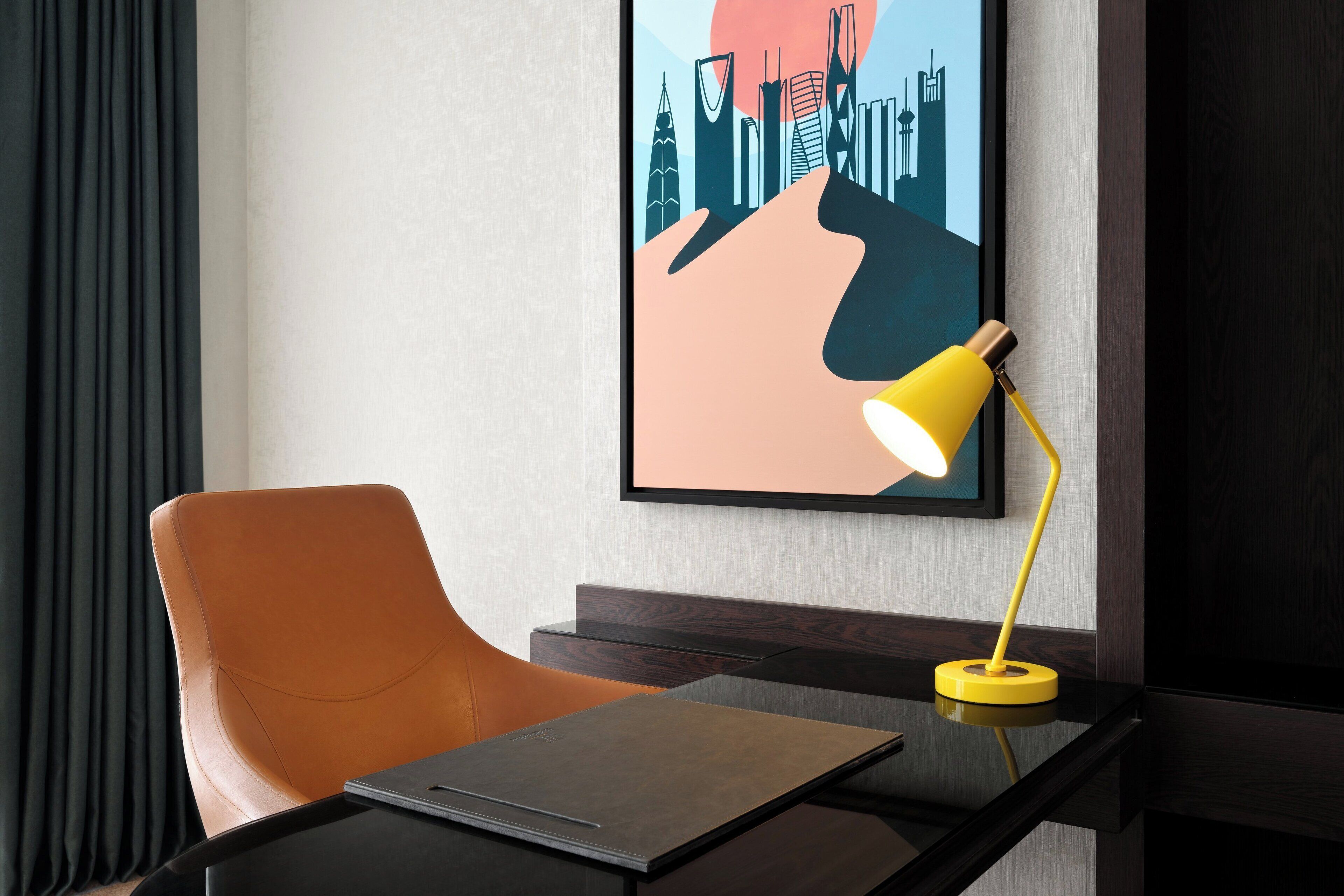 A modern office chair, a desk with a laptop, and a yellow desk lamp.