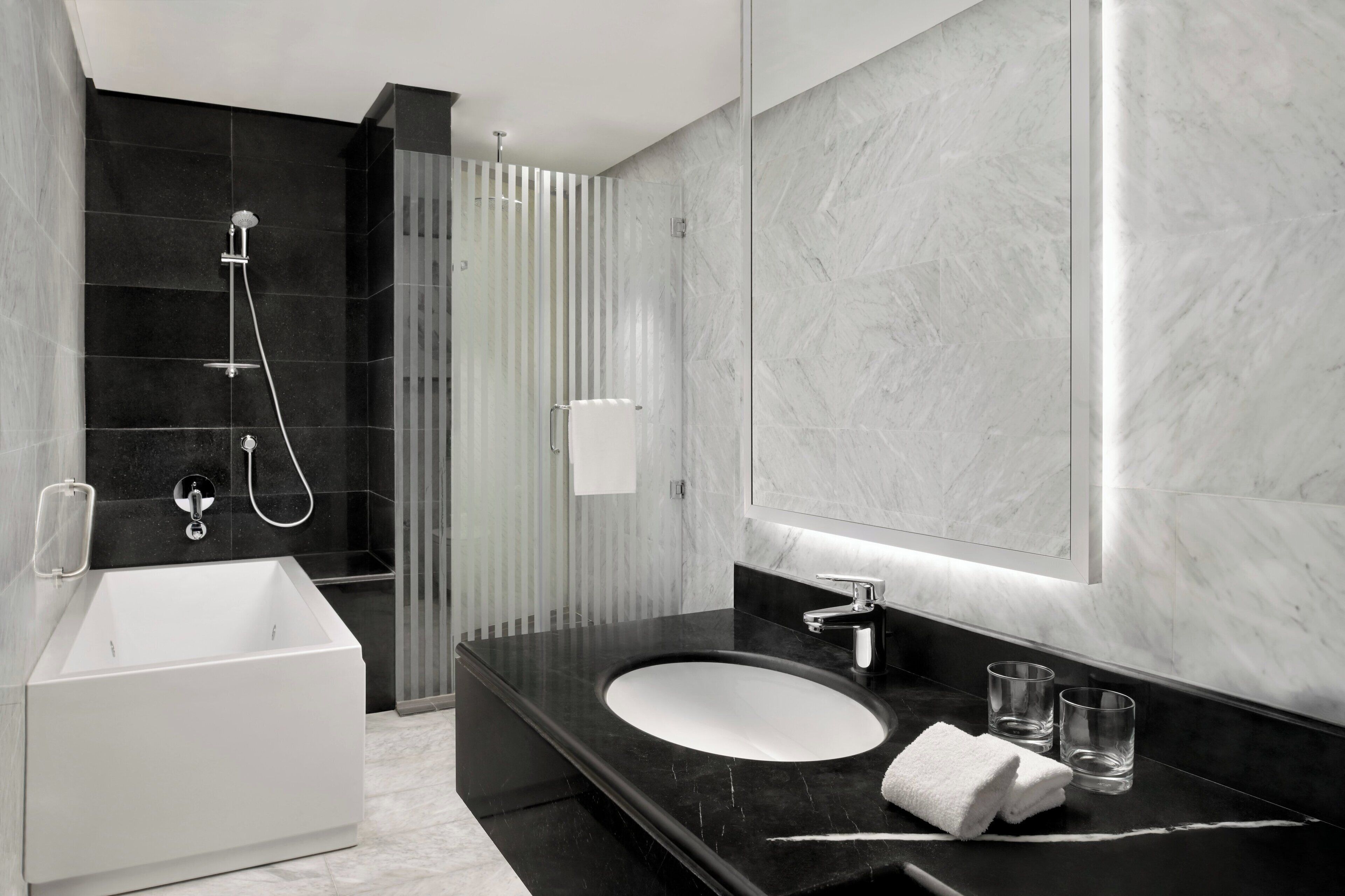 A modern bathroom with a freestanding bathtub, a sink with a marble countertop, and a large mirror.