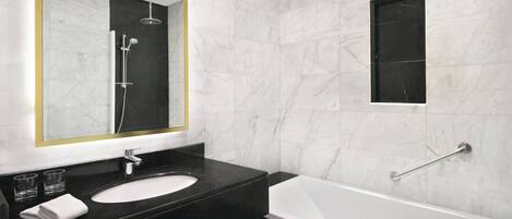 A modern bathroom with a black marble vanity, a white sink, and a white bathtub.