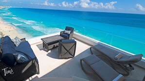 A sunlit outdoor seating area with a view of the ocean and beach. - Beachfront – 11BR/9Bth – Penthouse Combo #3120 (Cancun)