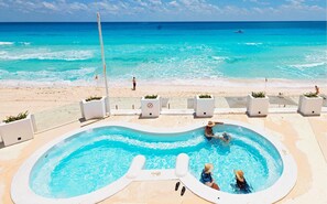 A swimming pool with a view of the ocean, surrounded by beach chairs and planters. - Beachfront – 11BR/9Bth – Penthouse Combo #3120 (Cancun)
