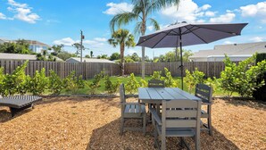 A backyard with a wooden table and chairs, a large umbrella, and a wooden fence. - Winter Getaway Stuart - Bring your truck, boat or RV - Large Fenced Yard (Stuart)