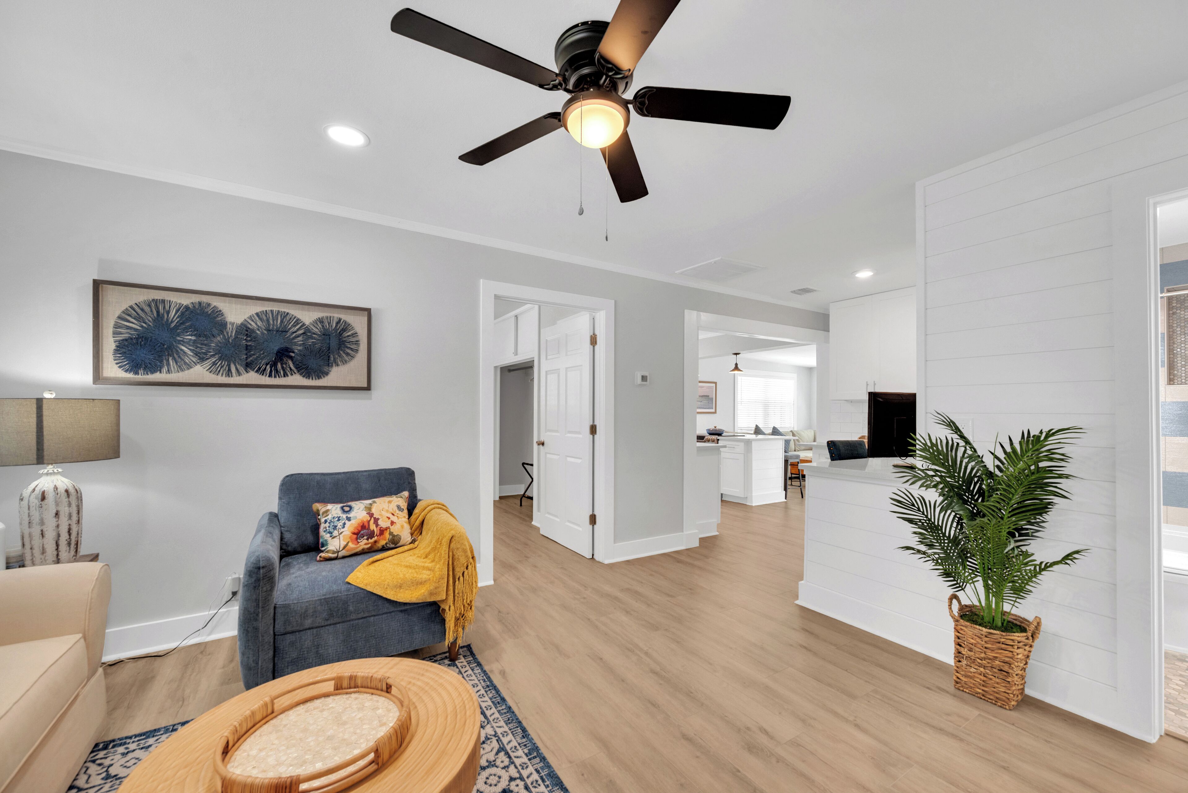 A modern living room with a ceiling fan, a sofa, a coffee table, and a dining area in the background.