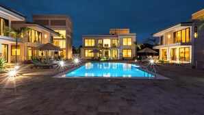 Un hôtel moderne doté d’une piscine, d’un espace extérieur aménagé et de balcons bien éclairés.