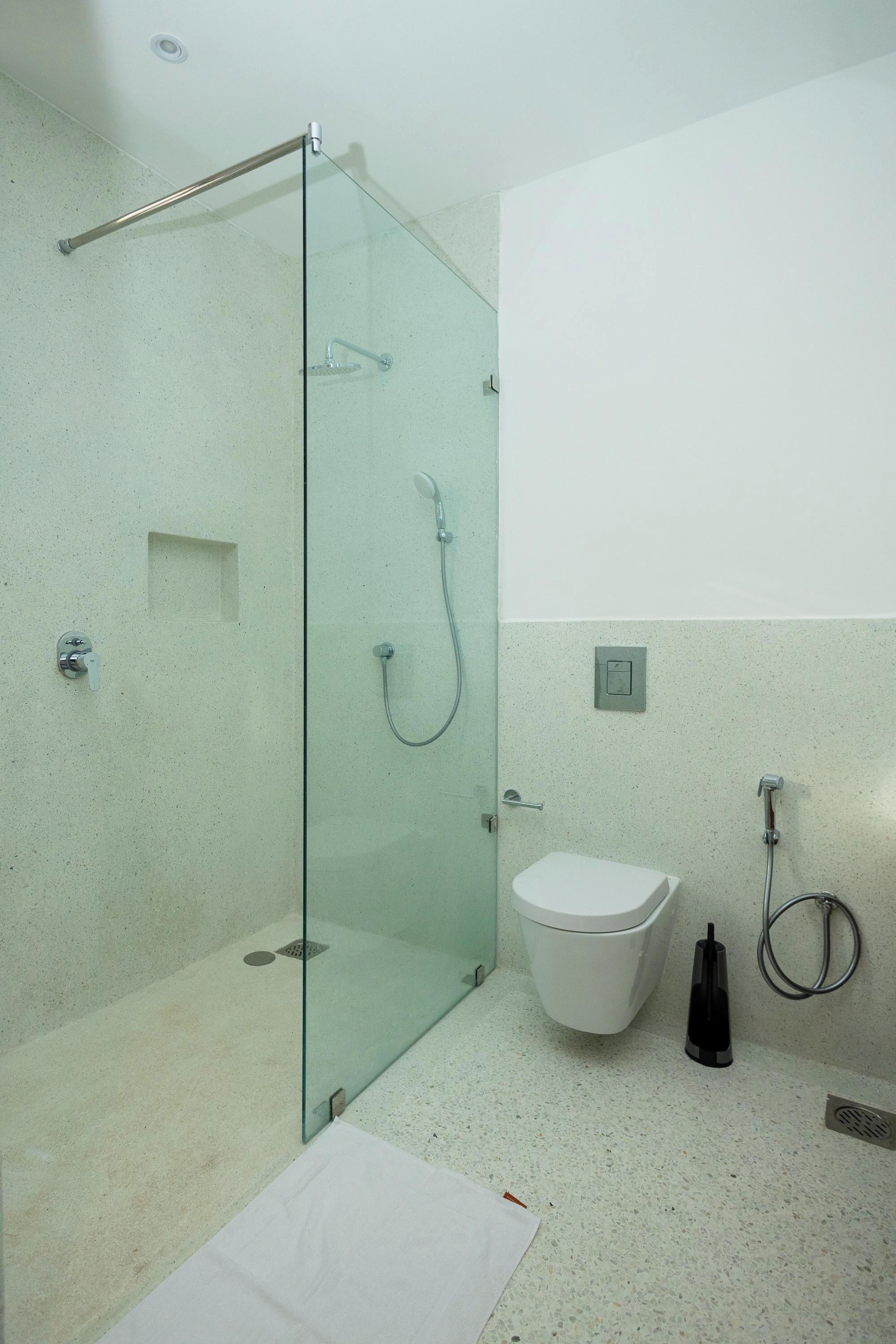 Un baño moderno con cabina de ducha de vidrio, inodoro blanco y ducha de mano.