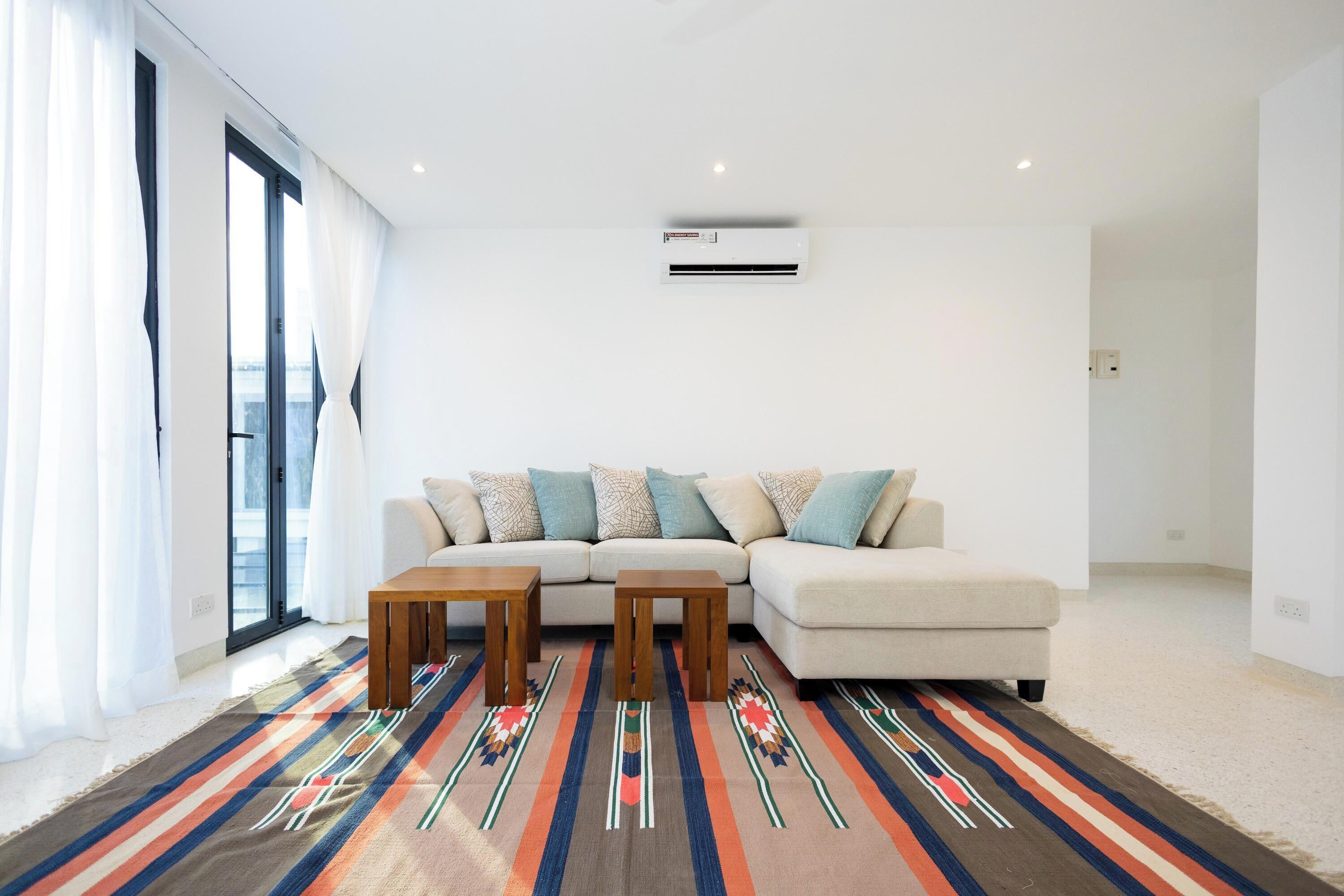 A modern living room with a sofa, two wooden side tables, and a colorful striped rug.