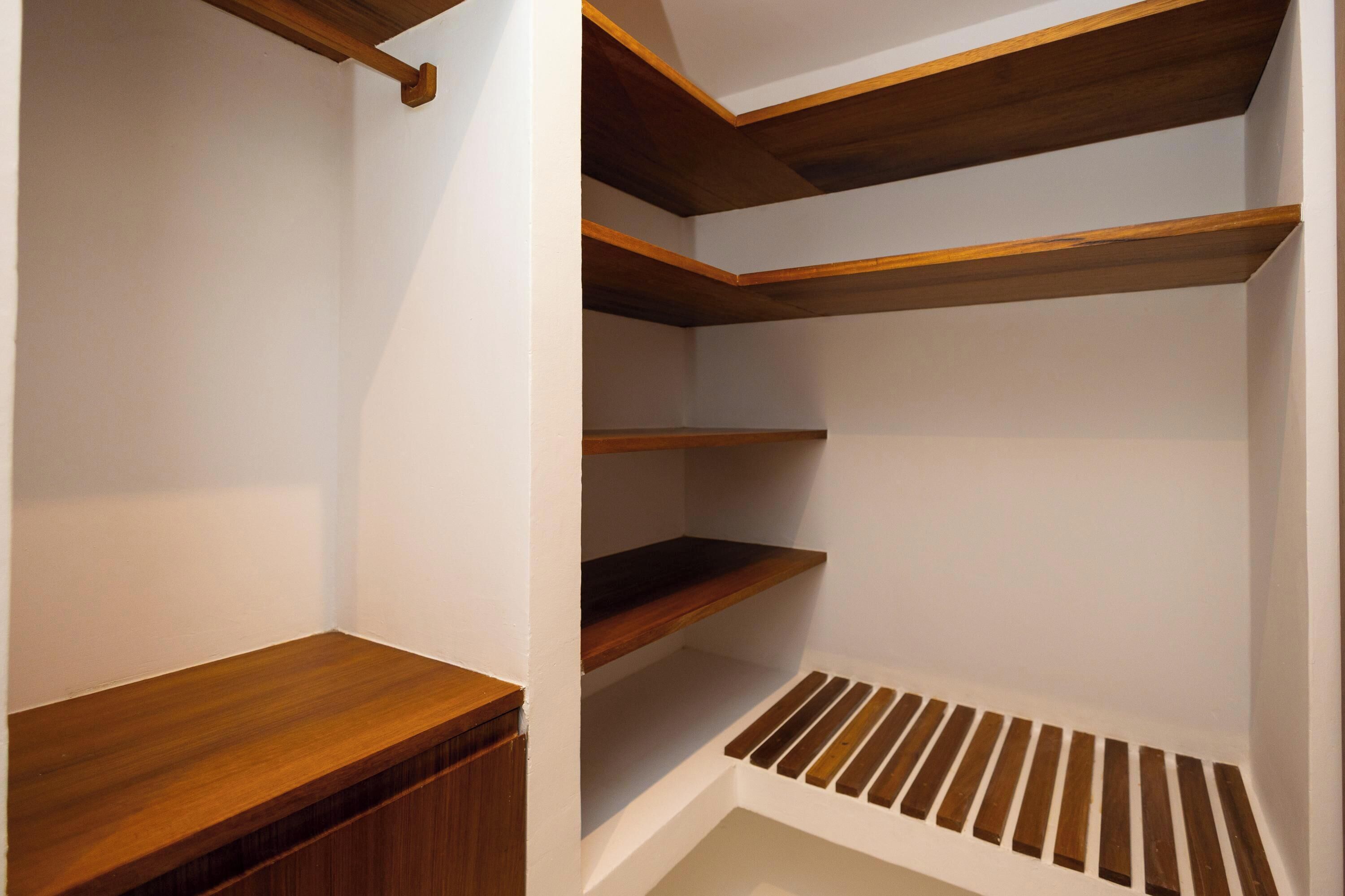 Un vestidor con estantes de madera y un banco incorporado.