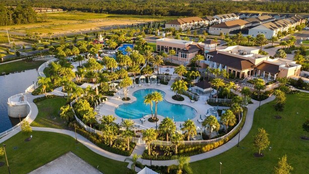 Un complexe hôtelier doté d’une piscine centrale, entourée de palmiers et de villas destinées aux clients.