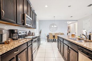 Kitchen features a round dining table, stainless steel appliances, and a dishwasher.