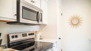 Eine Küche mit Herd, Backofen, Mikrowelle und einem dekorativen Sonnenspiegel an der Wand.