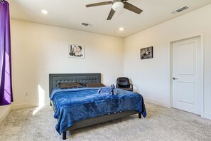 Une chambre à coucher avec un lit, un ventilateur de plafond, une porte et une chaise.