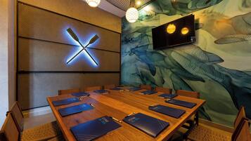 A conference room with a large wooden table, chairs, and a wall-mounted clock.