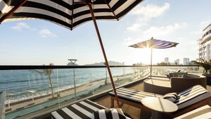 A rooftop lounge with striped lounge chairs, a pool, and a view of the ocean and city skyline. - Holiday Inn Express & Suites Hotel Mazatlan by IHG (Mazatlán)