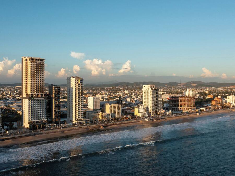A coastal cityscape with high-rise buildings, a beach, and a clear sky.