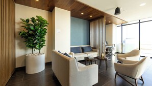 A modern living room with a sofa, two armchairs, a coffee table, and a large potted plant. - Holiday Inn Express & Suites Hotel Mazatlan by IHG (Mazatlán)