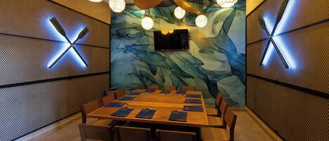 Un salón de conferencias con una larga mesa, sillas y una pantalla grande.
