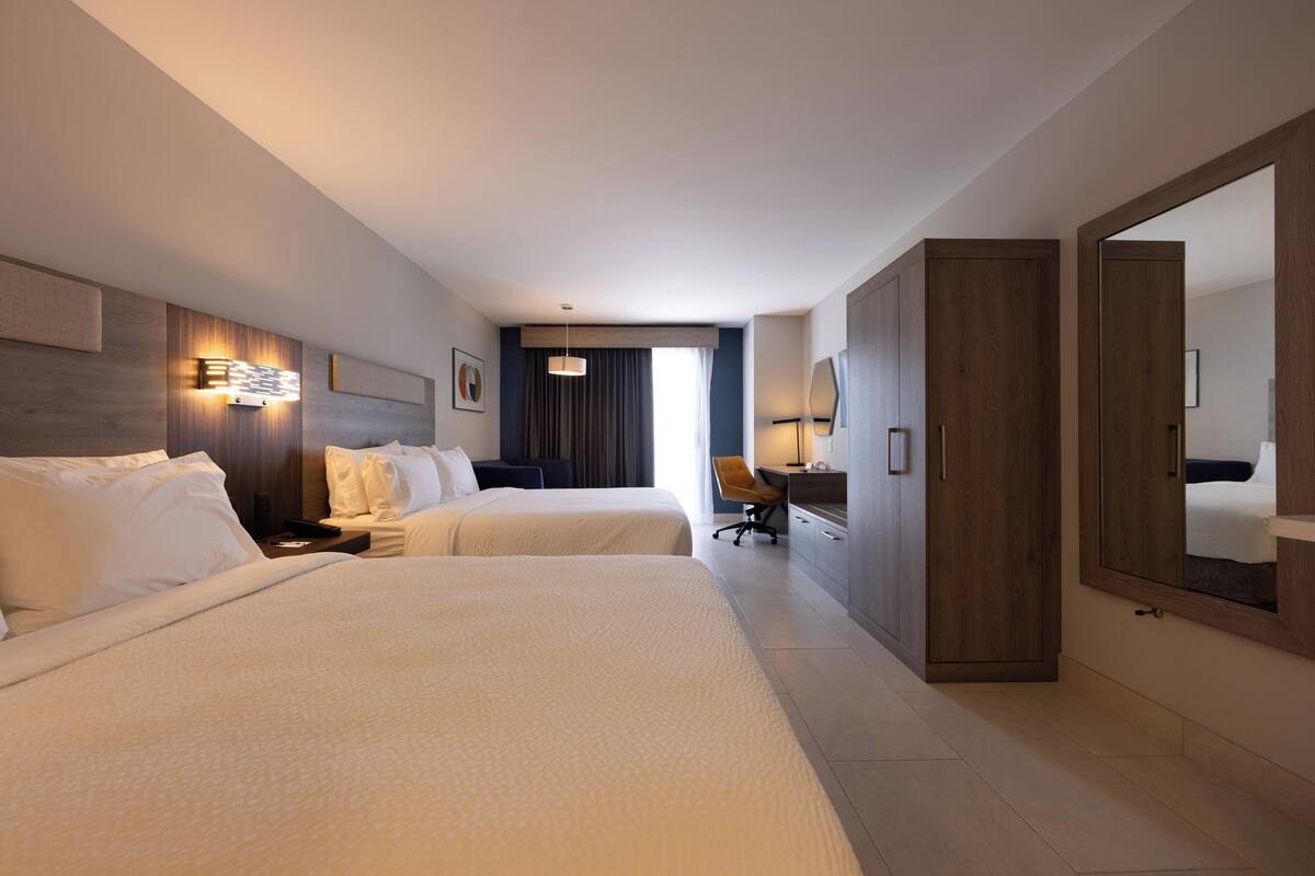 Ett hotellrum med två sängar, ett skrivbord, en stol och en garderob.
