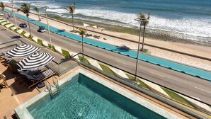 A pool with clear water, a beach view, and a road with palm trees. - Holiday Inn Express & Suites Hotel Mazatlan by IHG (Mazatlán)