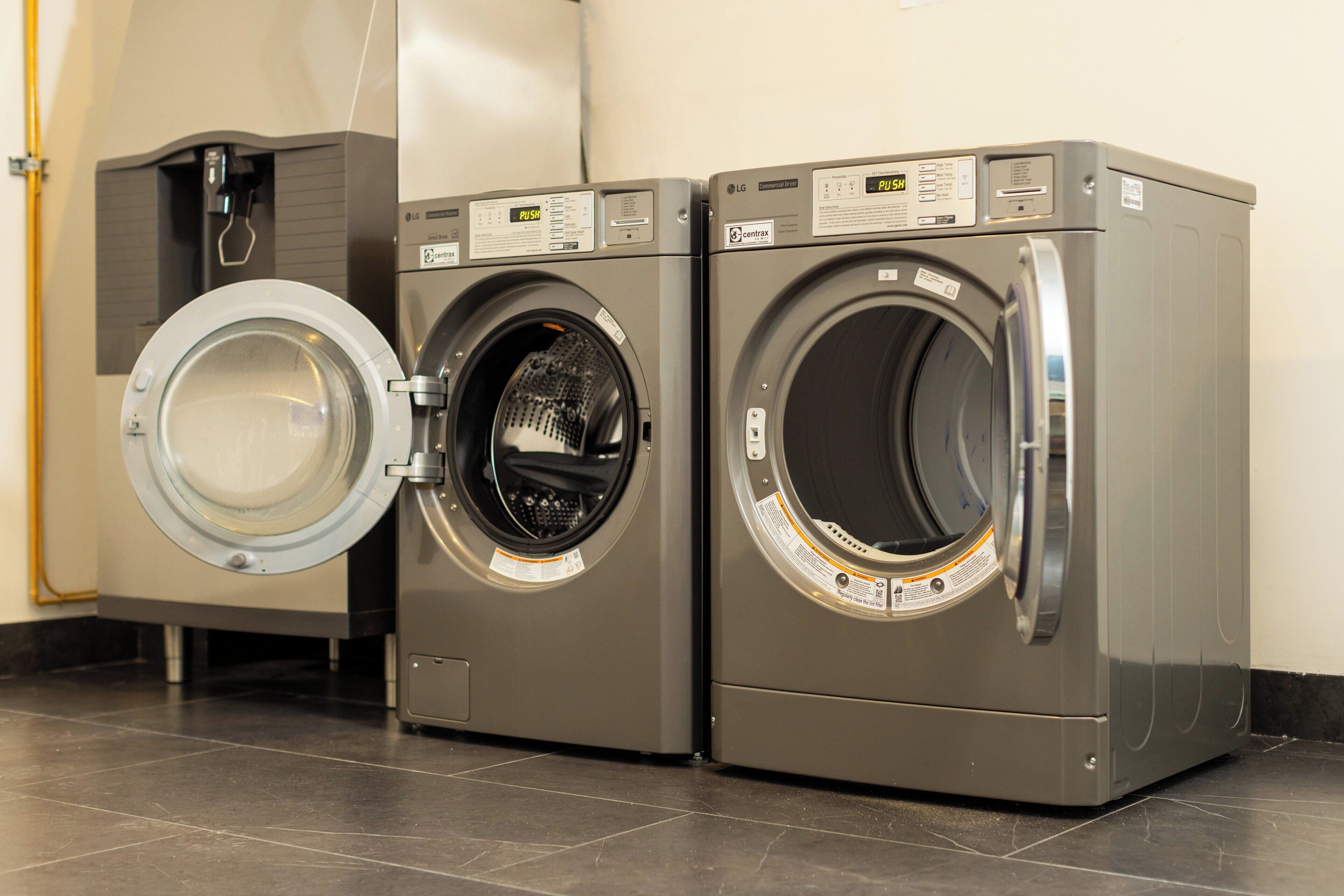 Two commercial dryers with control panels, one with its door open.