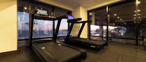 Ein Fitnessraum mit Laufbändern und einem großen Fenster.