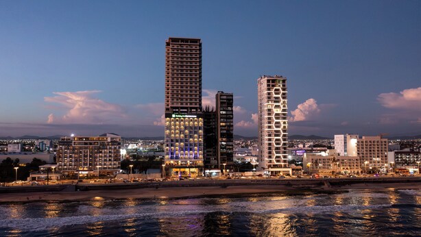 A cityscape with high-rise buildings, including a hotel with a prominent sign. - Holiday Inn Express & Suites Hotel Mazatlan by IHG (Mazatlán)