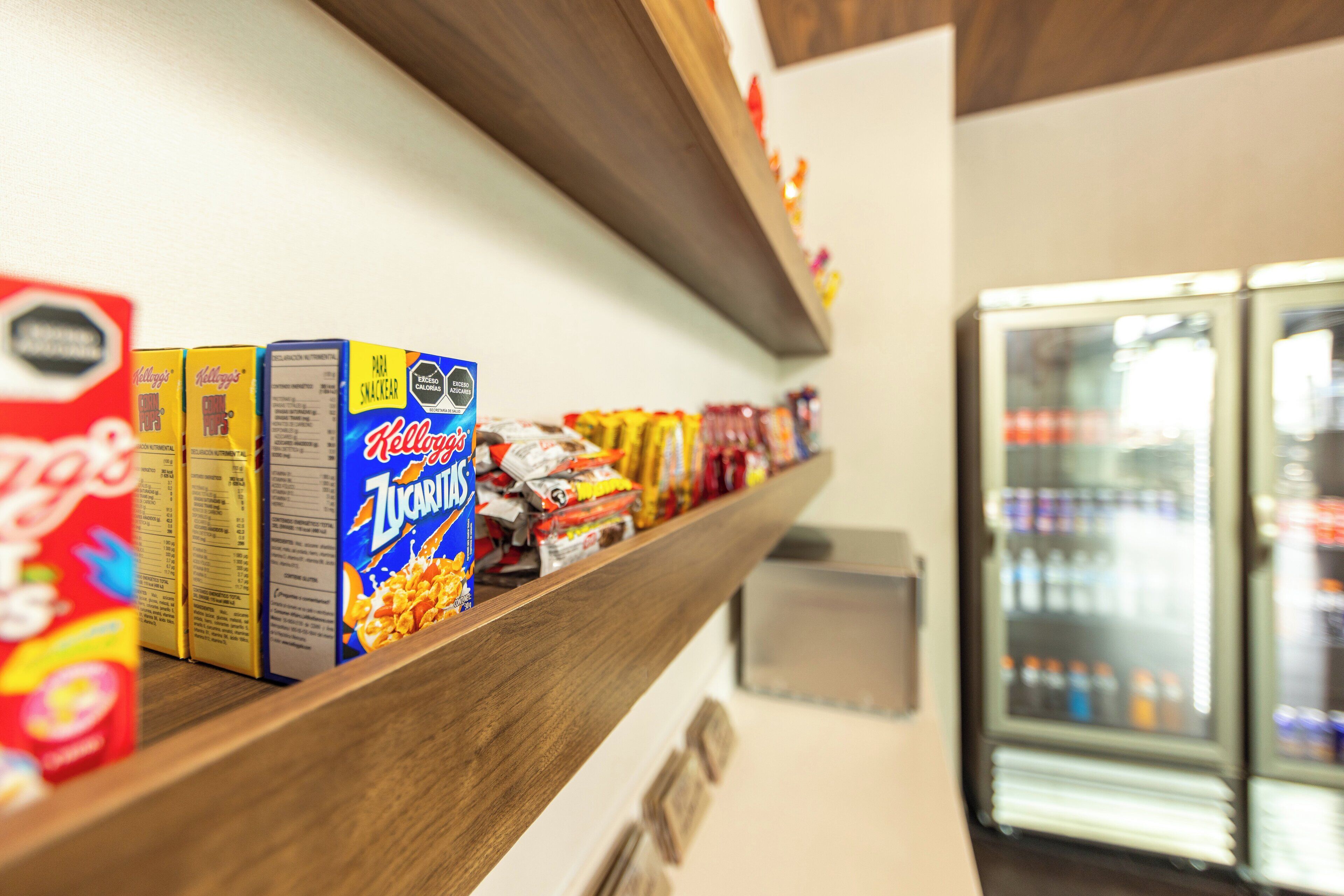 A snack bar with various packaged foods and a refrigerator in the background.