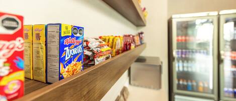 A snack bar with various packaged foods and a refrigerator in the background.