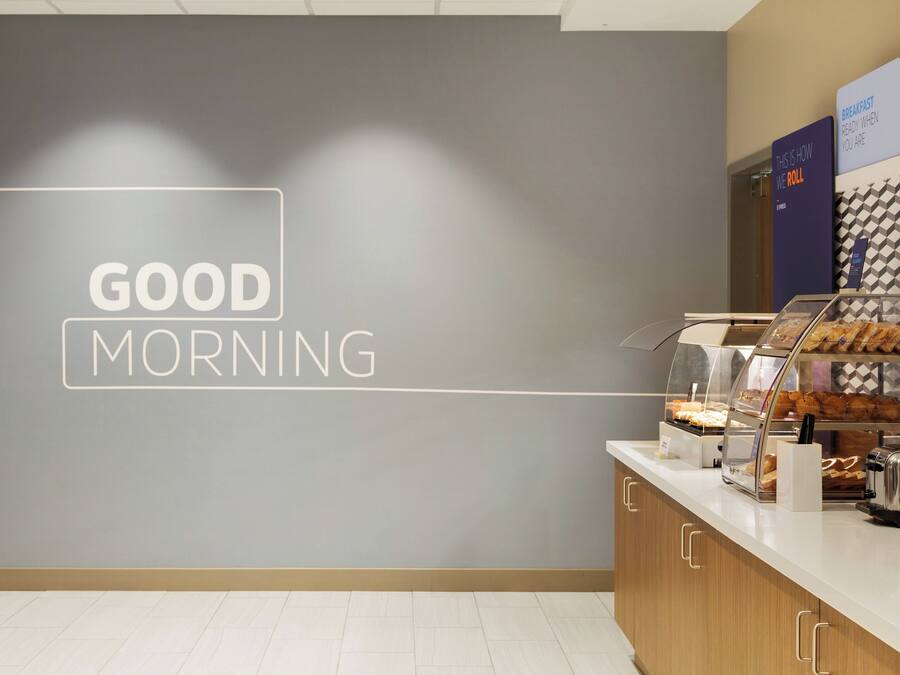 Una barra de desayuno con un letrero que dice 'GOOD MORNING', una máquina de café y pasteles.
