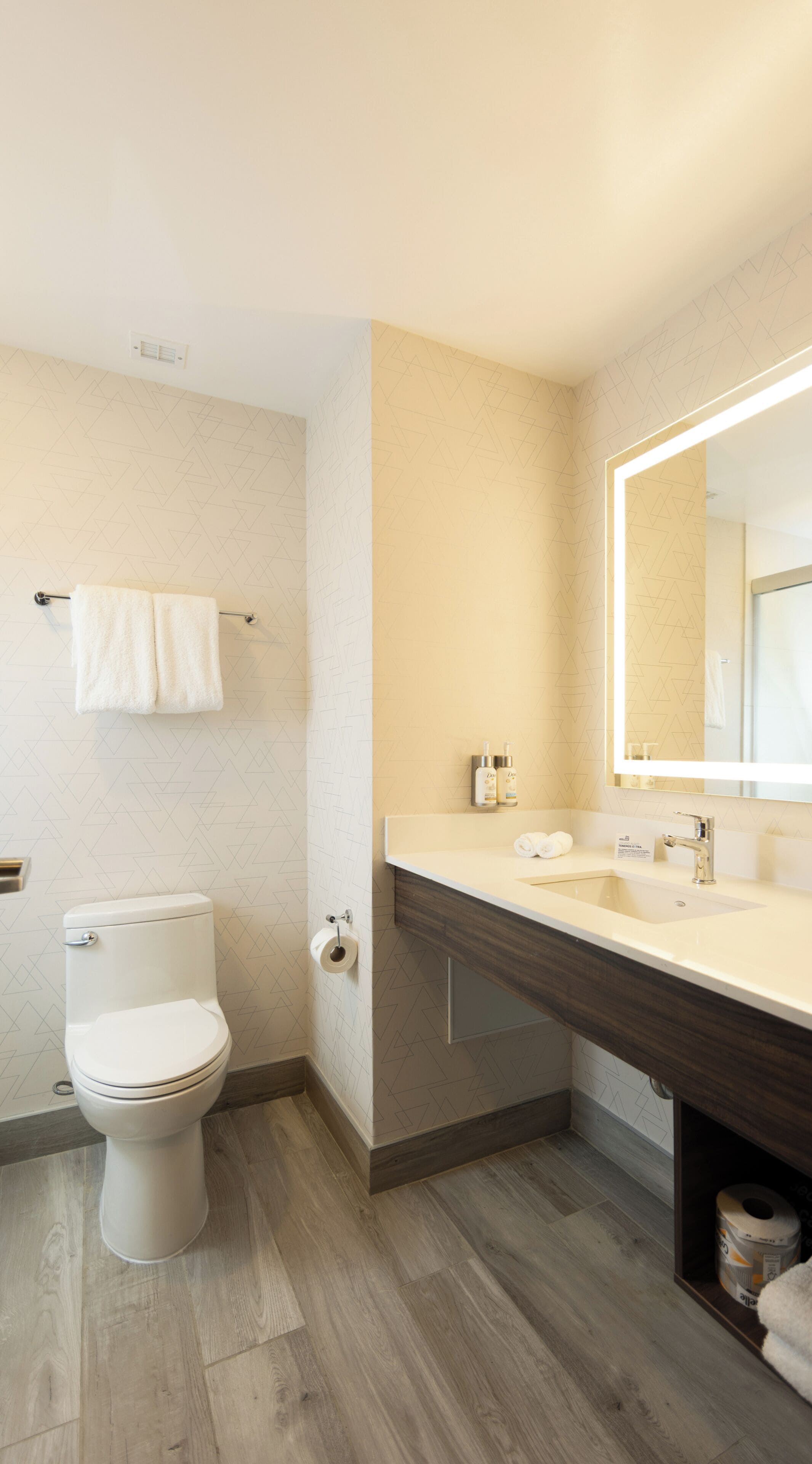 Ein modernes Badezimmer mit Toilette, Waschbecken und Spiegel.