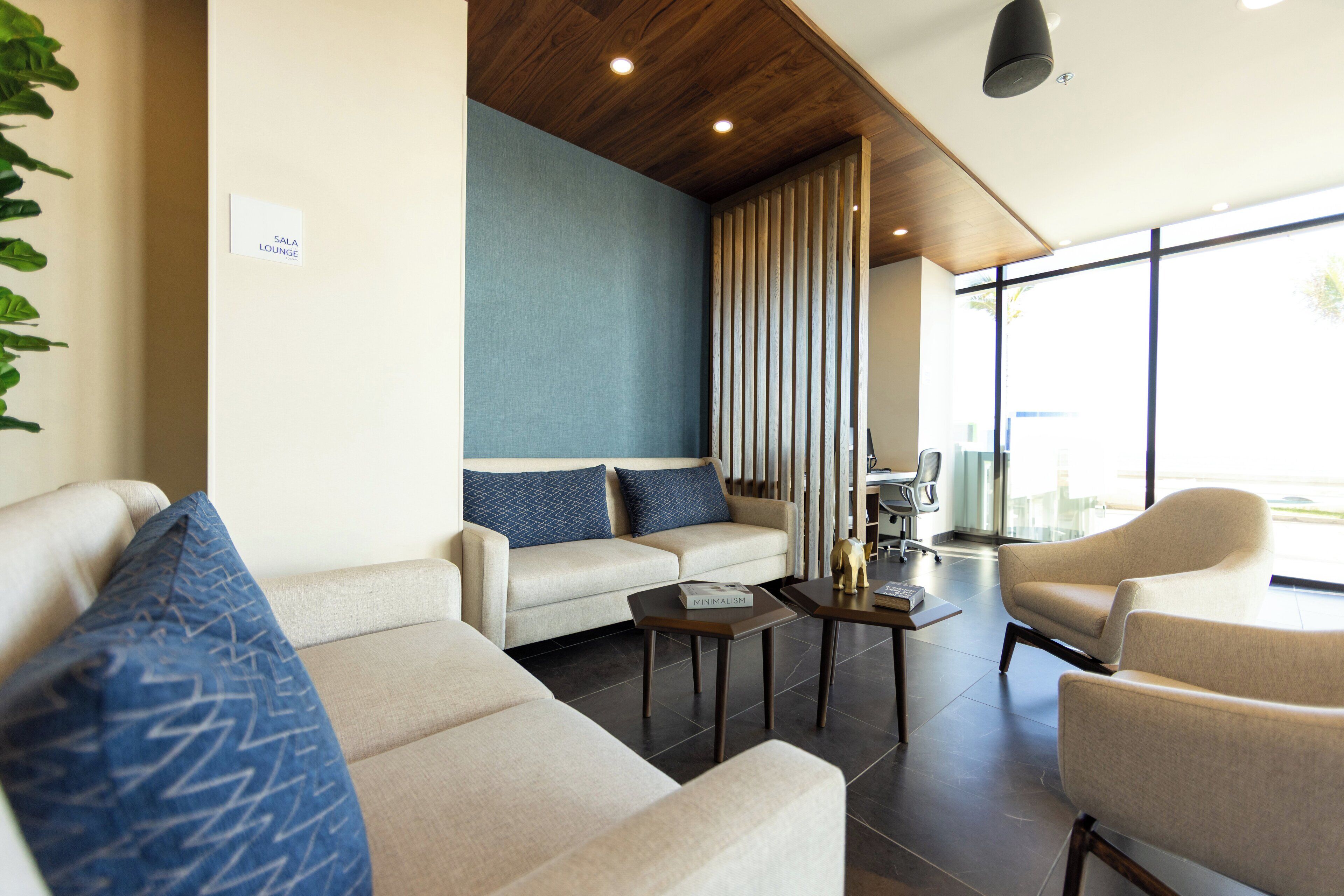 A modern lounge area with a sofa, armchairs, a coffee table, and a bookshelf.