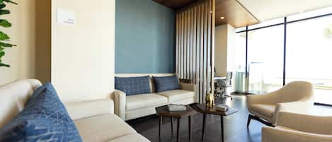 A modern lounge area with a sofa, armchairs, a coffee table, and a bookshelf.