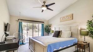 Ein Schlafzimmer mit Bett, Schreibtisch, Stuhl und Deckenventilator.