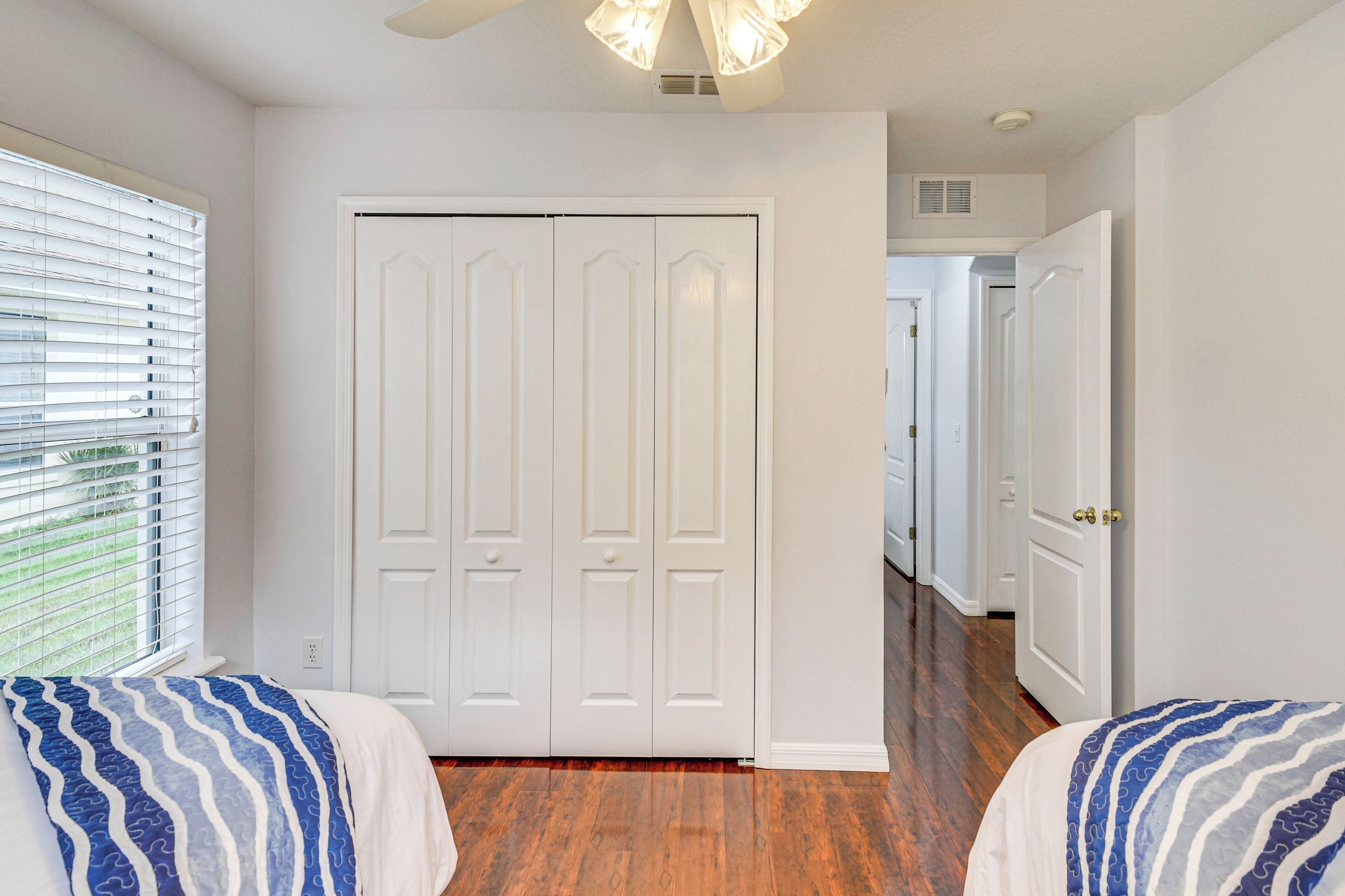 A bedroom with a large closet, wooden flooring, and a ceiling fan.