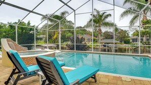 An indoor swimming pool with lounge chairs and a glass enclosure.