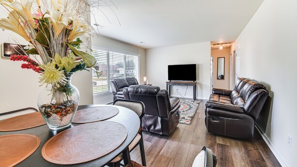 A modern living room with a leather sofa, a dining table with placemats, a flat-screen TV, and a decorative vase with flowers. - 3 Mi to Huntington Beach: Hampton Family Home! (Hampton)