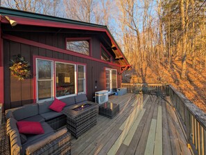 A wooden deck with outdoor seating and a fire feature.