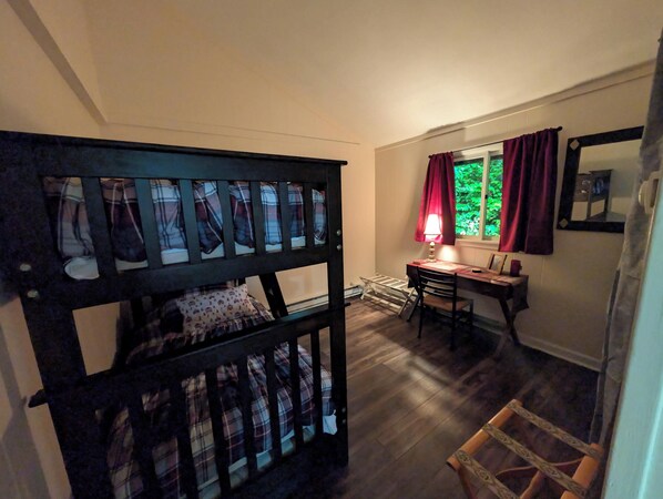 A room with a bunk bed, a desk with a lamp, and a window with curtains.