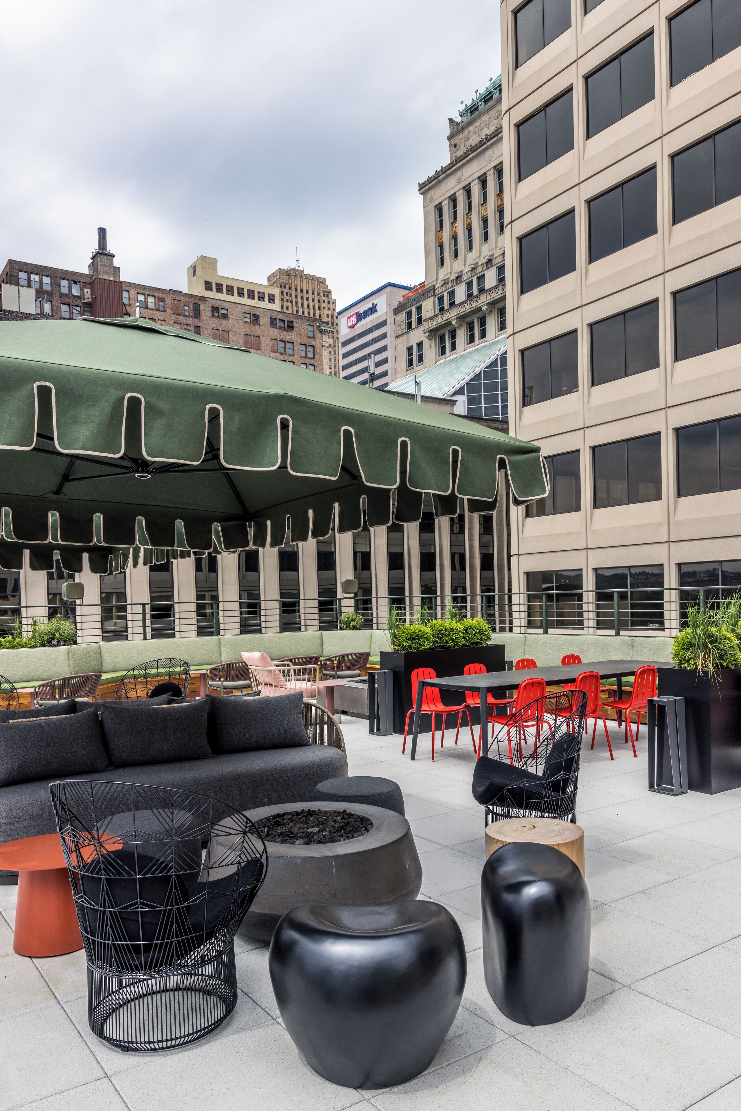 Een terras met moderne meubels, een groene parasol en uitzicht op de stad.