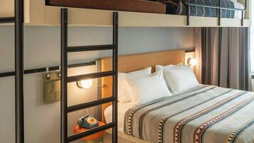 A bunk bed room with a ladder, a bedside table with a lamp, and a patterned bedspread.