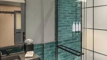 A modern bathroom with a glass shower enclosure, a vanity with a mirror, and a towel rack.