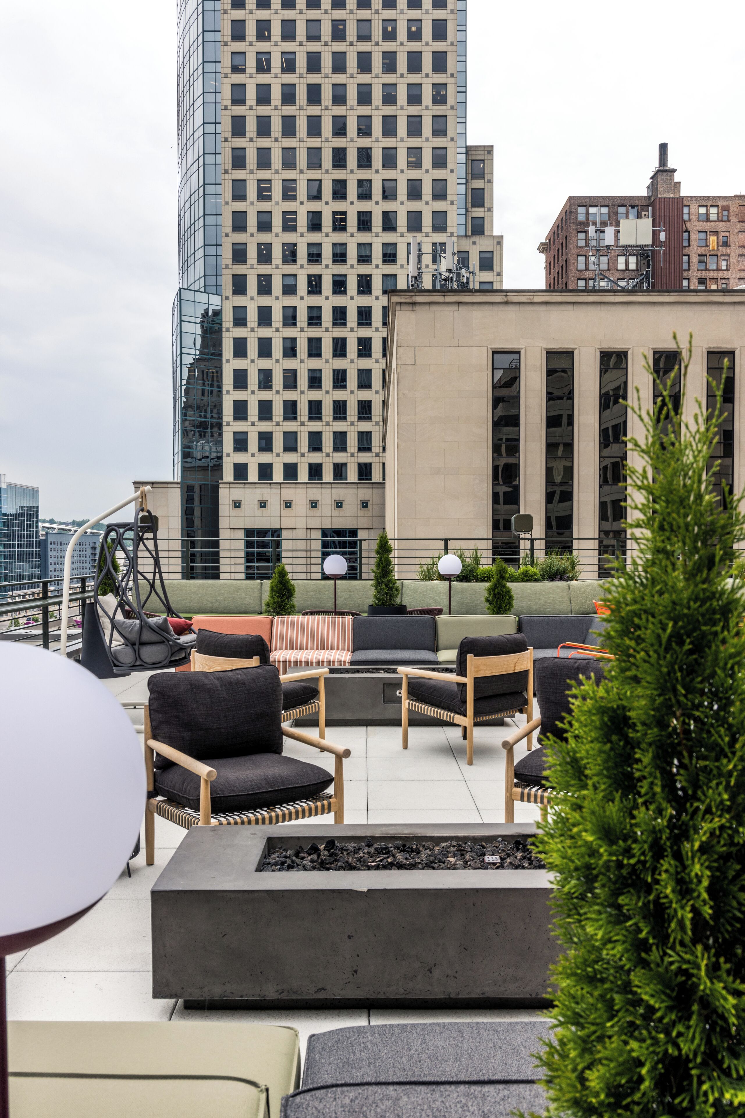 A rooftop terrace with outdoor seating, a fire pit, and a view of surrounding buildings.