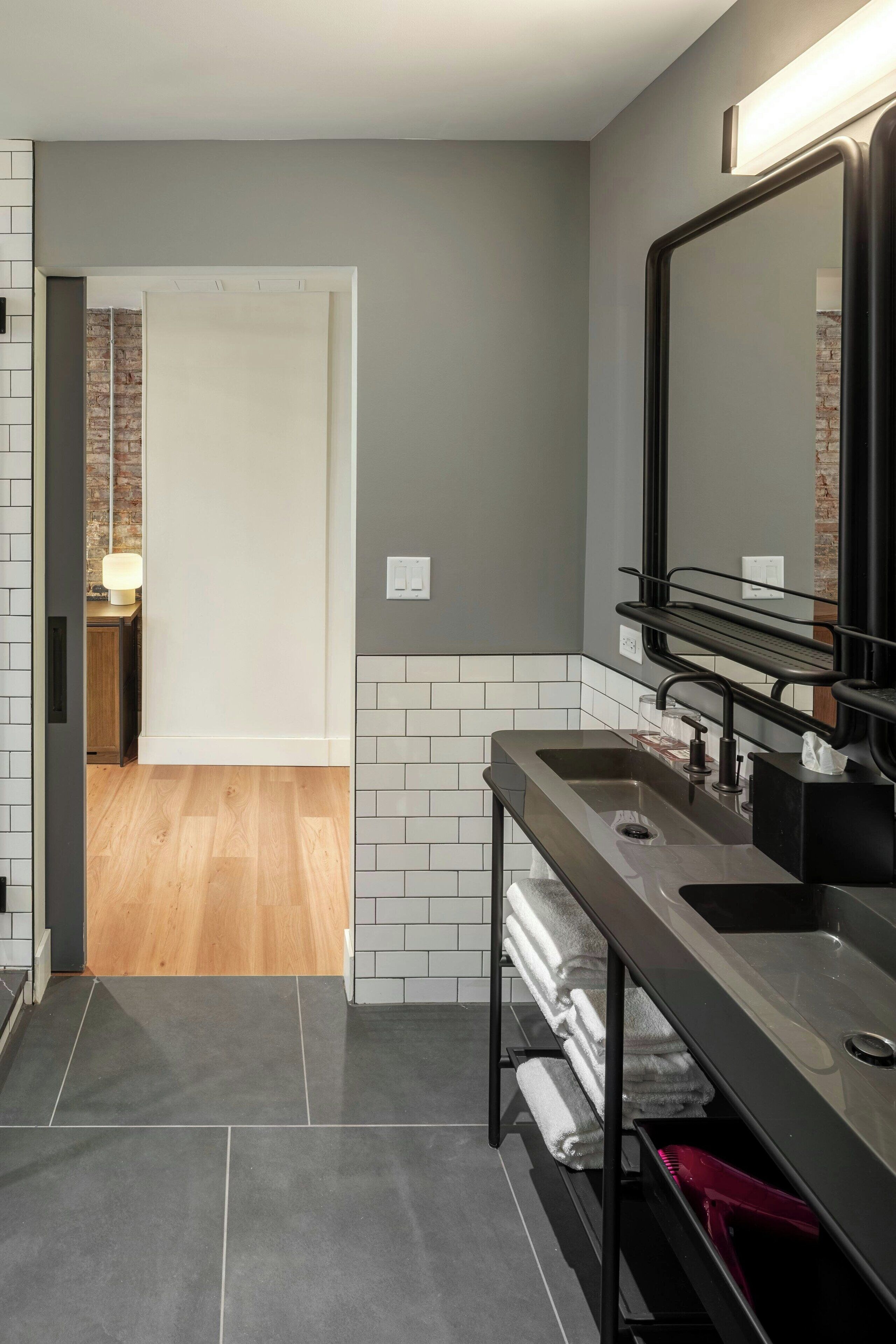 A modern bathroom with two sinks, a large mirror, and a towel rack.