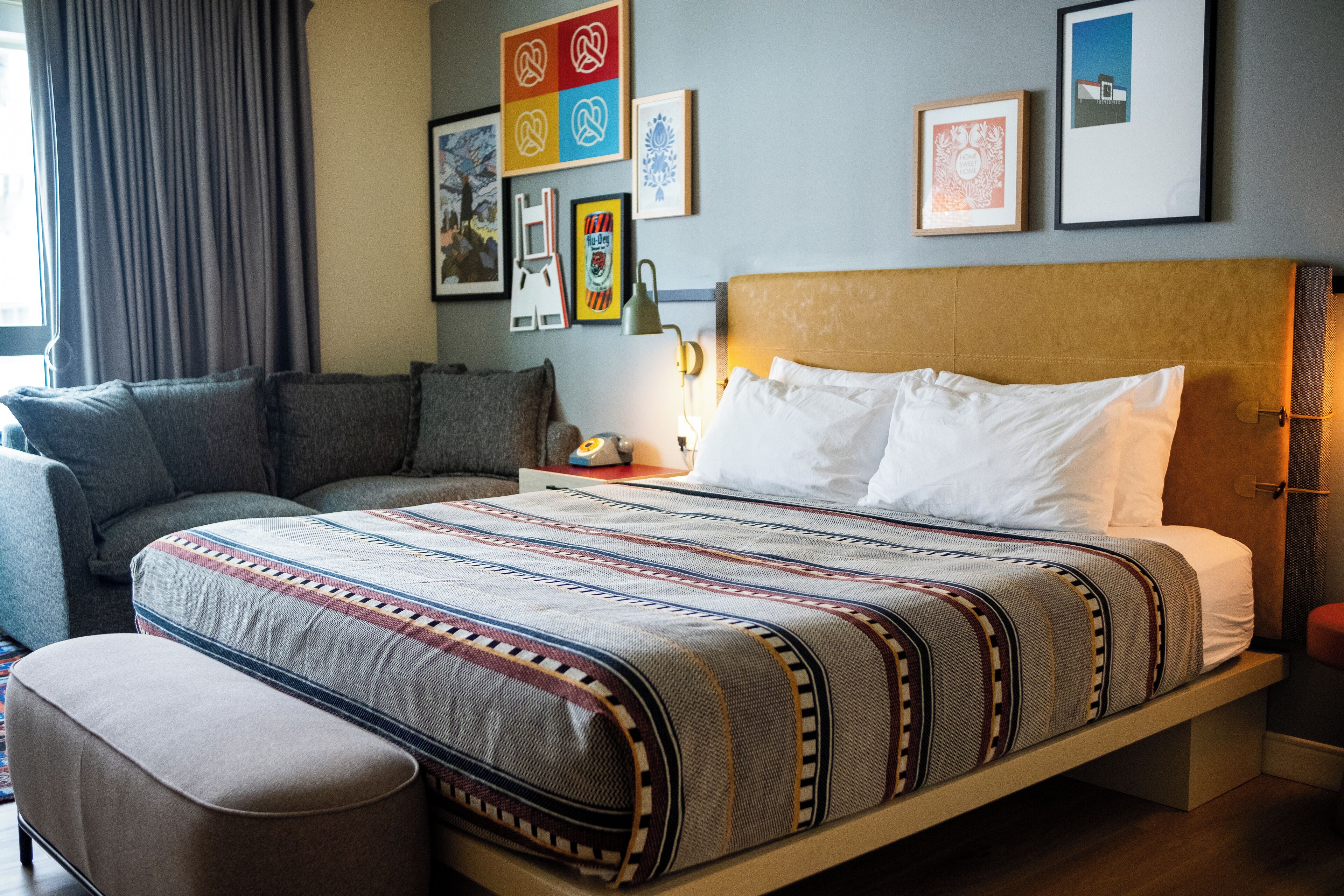 Una habitación de hotel ordenada con una cama grande, un sofá y una mesita.